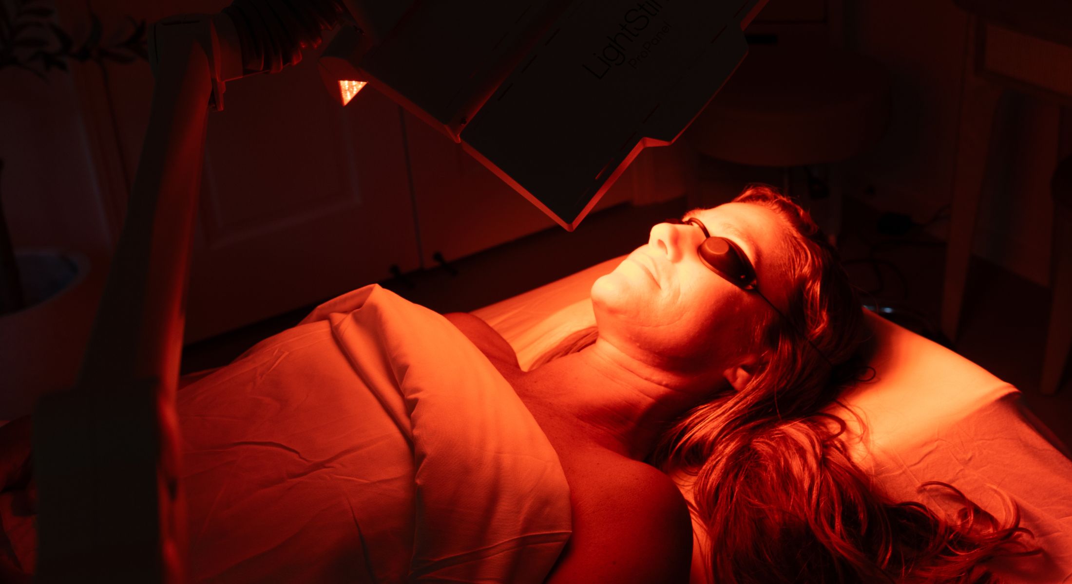 Woman undergoing red light therapy treatment.
